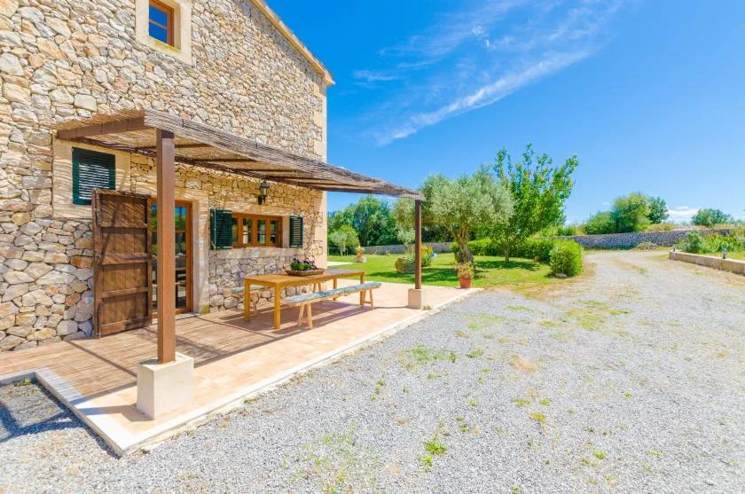 Una casa de piedra con un patio cubierto y un patio de grava.