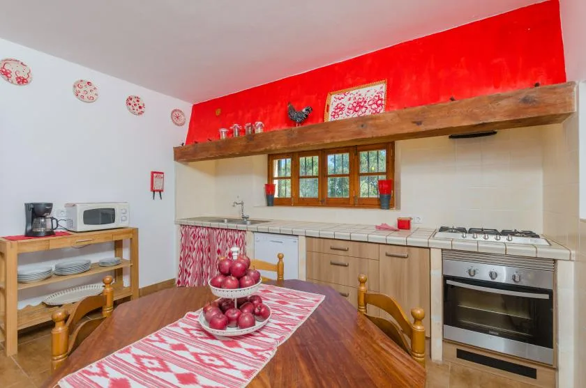 A bright kitchen with a long counter, wooden cabinets, and a dining table.
