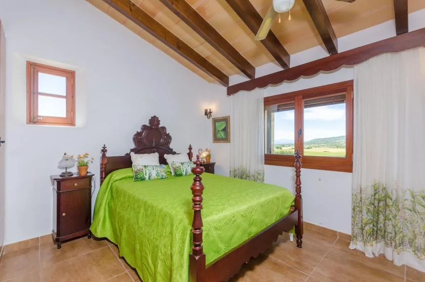 A bedroom with a carved wooden bed dressed in a bright green bedspread.
