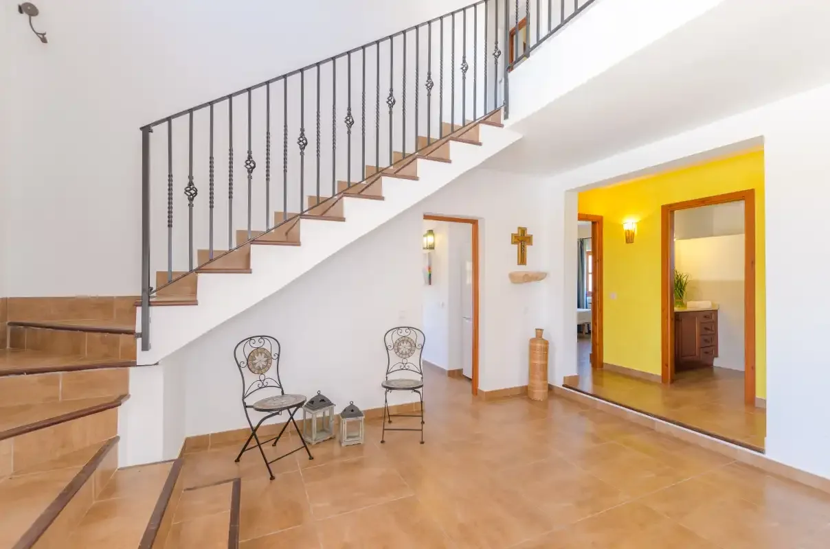A bright interior hallway features a staircase and two chairs.
