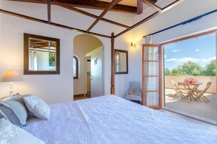 A bedroom with a bed beside open doors leading to a patio.