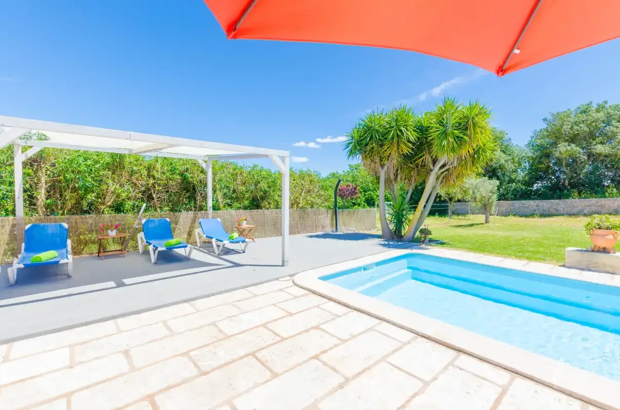An outdoor pool beside a shaded seating area and garden.