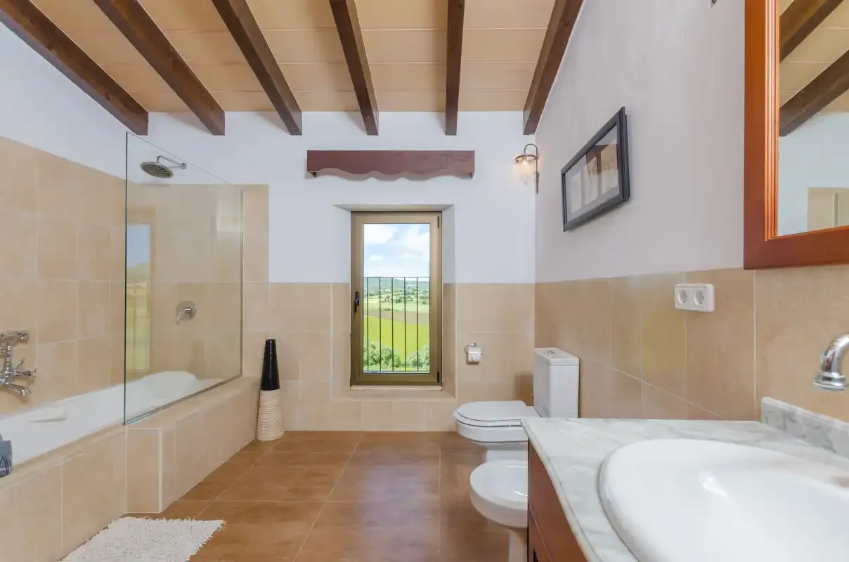 A bathroom with a shower, bathtub, and window overlooking green fields.