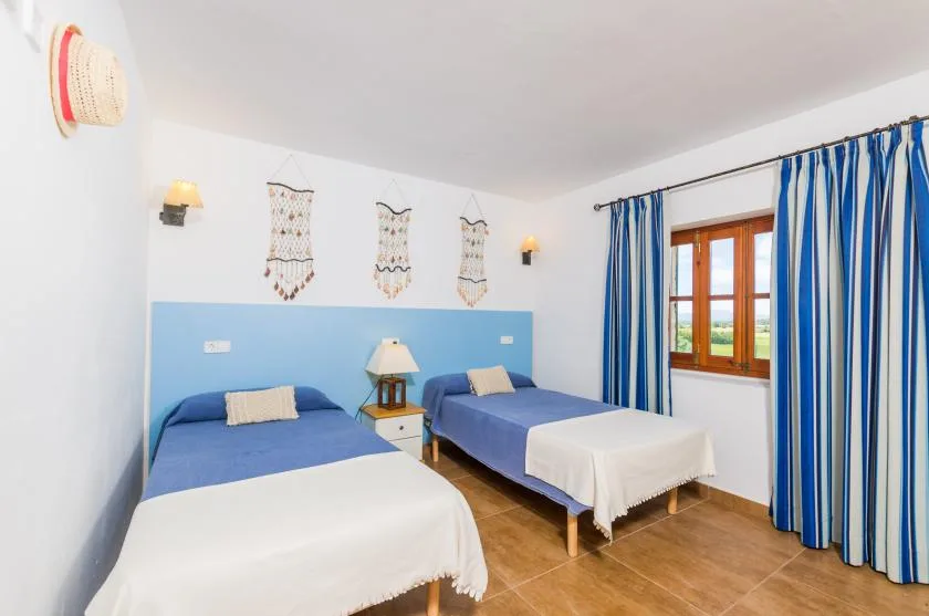 A bedroom with two blue beds and blue-and-white curtains.