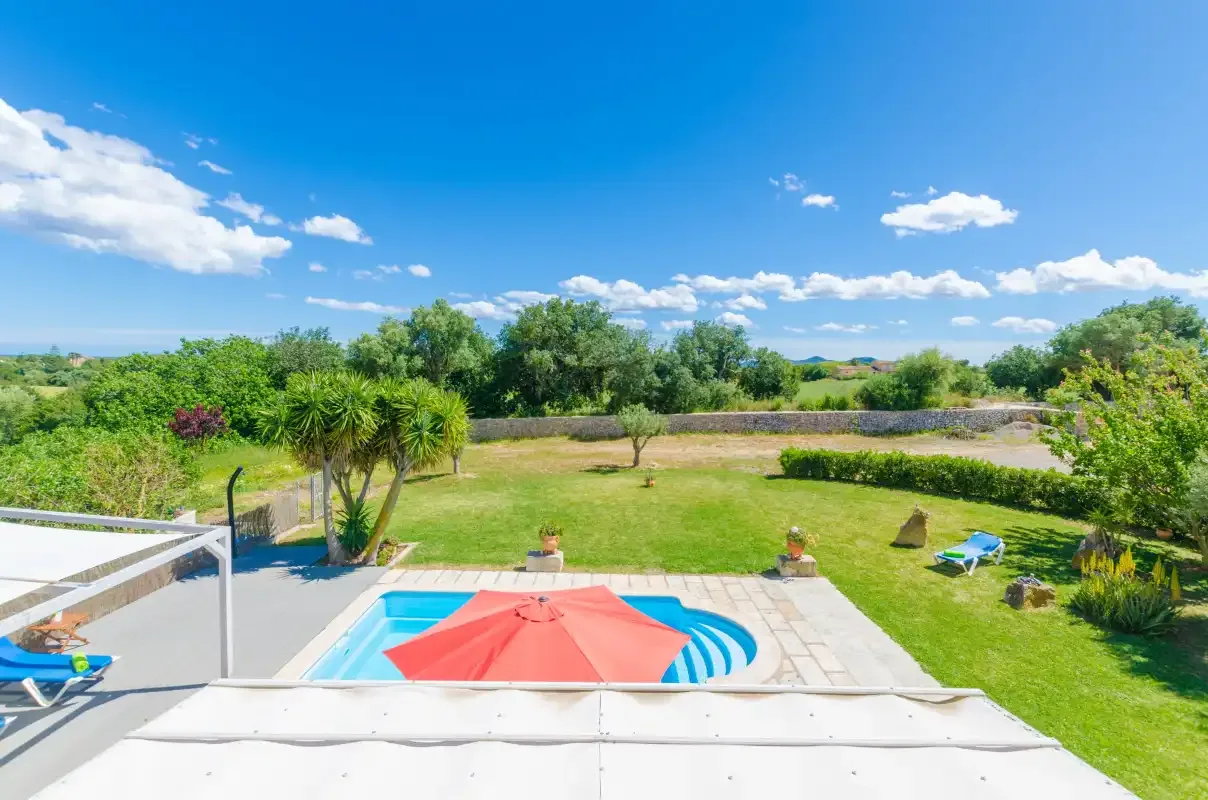 A swimming pool and patio overlook a green garden and surrounding countryside.
