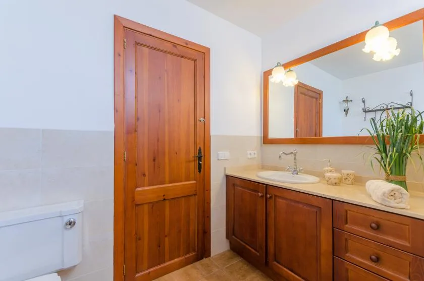 A bathroom vanity with a sink and mirror stands beside a wooden door.