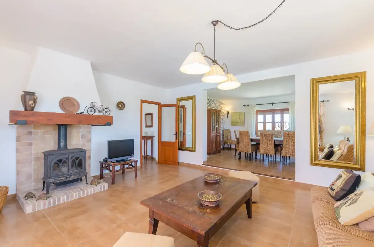 A living room with a fireplace, seating, and a view into the dining area.