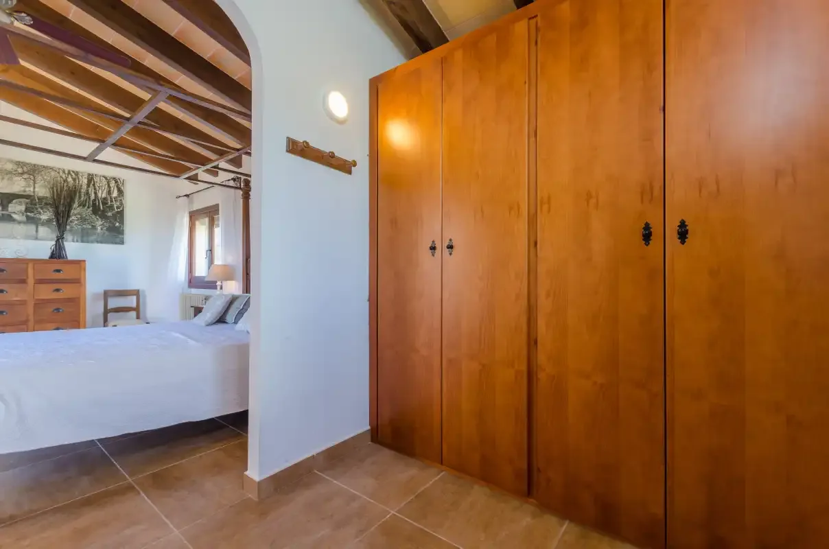 A bedroom with a bed beside a large wooden wardrobe.