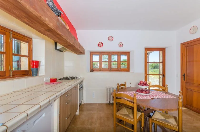 A kitchen and dining area with tiled counters and a wooden dining table.