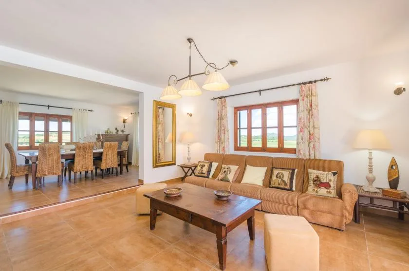 Living room with seating around a wooden coffee table and dining area beyond.