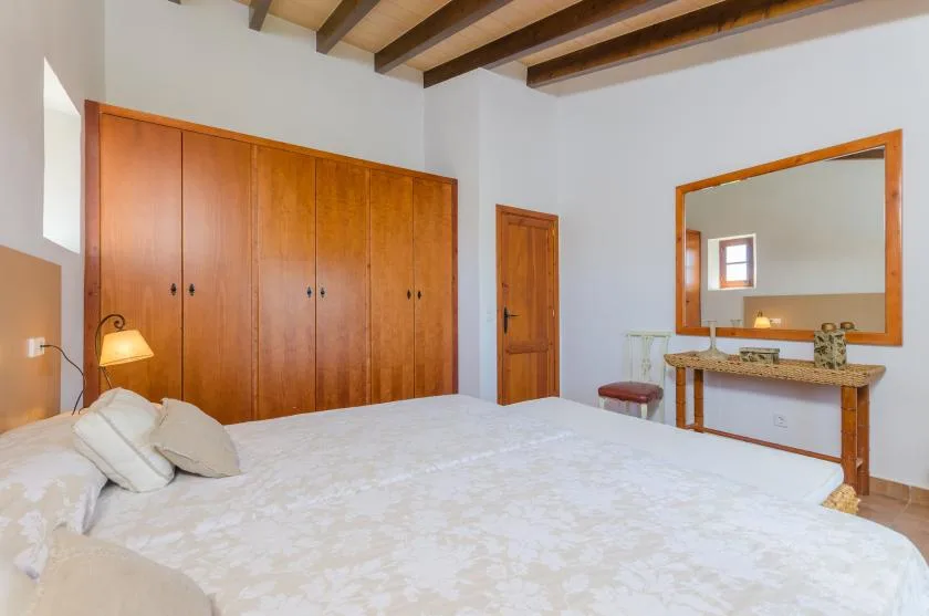 A bedroom with a large bed, wooden wardrobes, and a wall mirror.