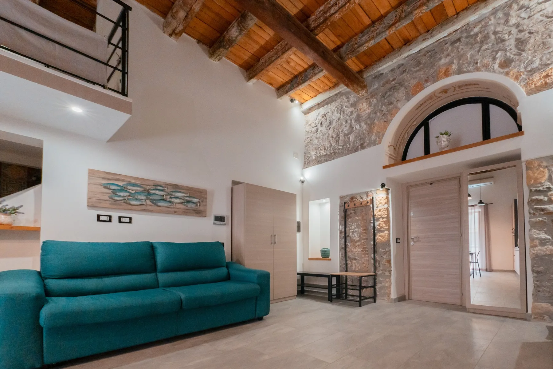 A living room with teal seating beneath a high timber ceiling.