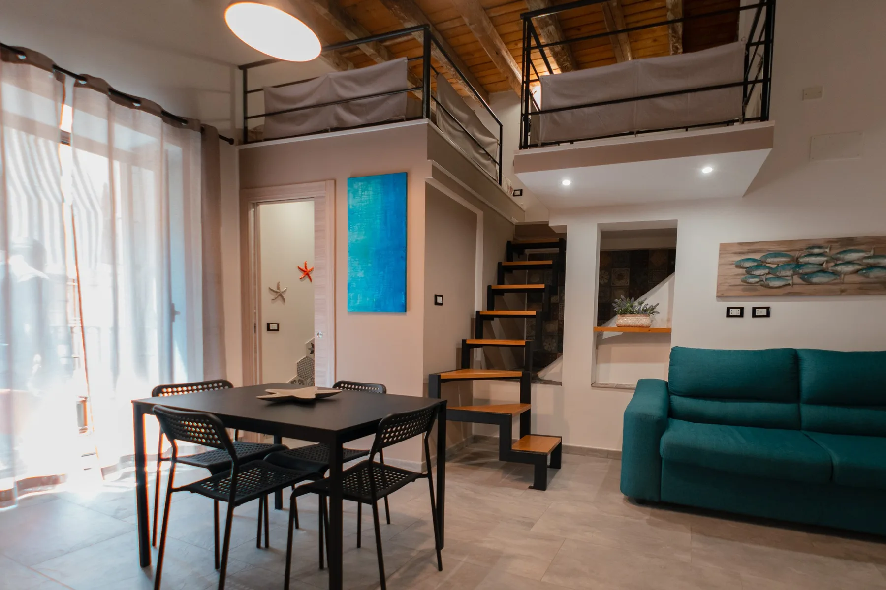 A loft-style living and dining area with a table, seating, and an overhead sleeping platform.