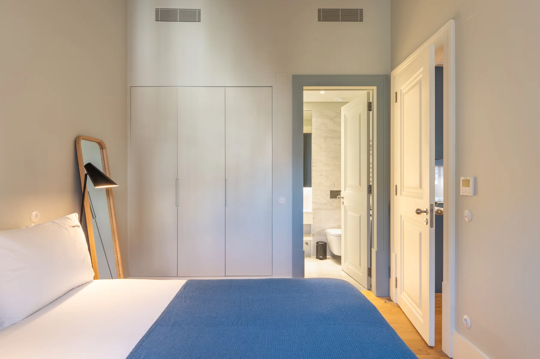 Un dormitorio con una cama y una puerta que da a un baño.