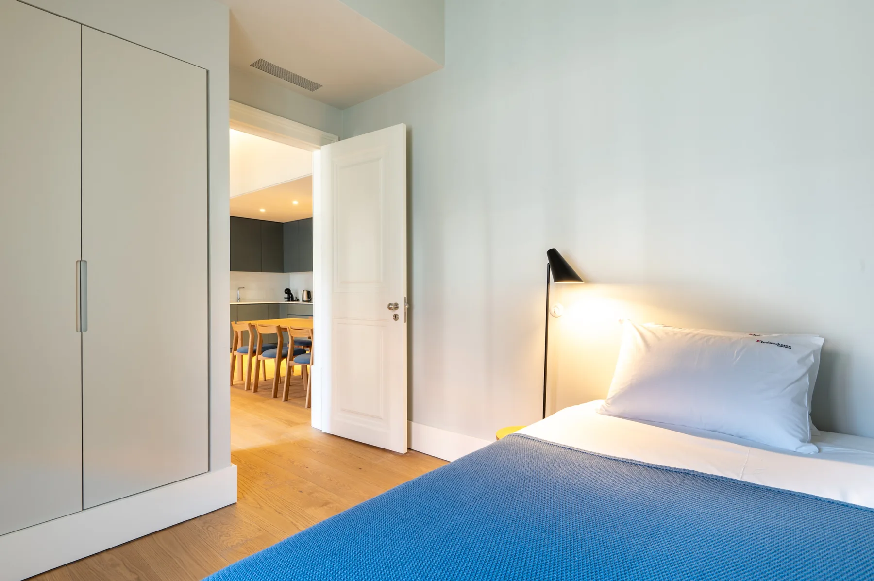 Un dormitorio con una cama y una puerta abierta hacia un comedor.