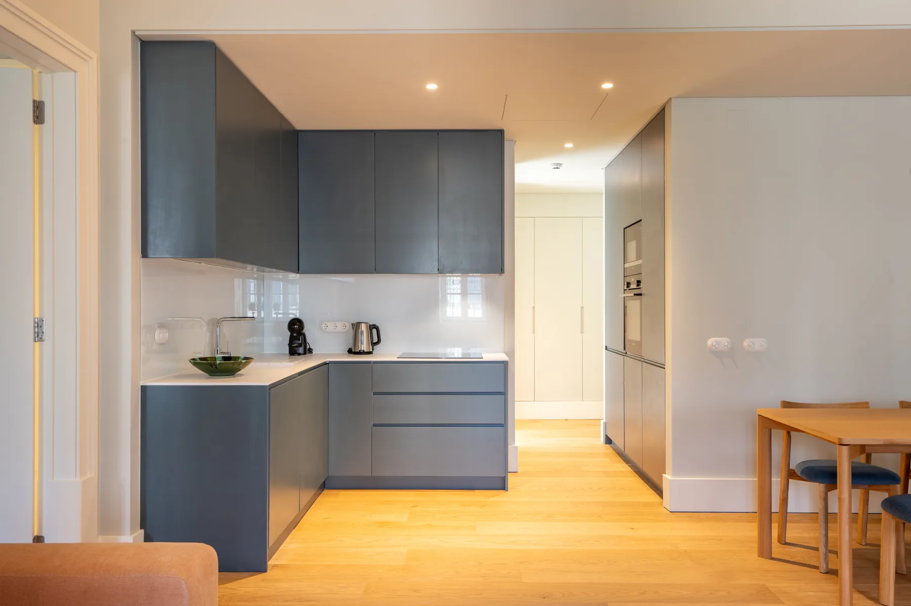 Una cocina moderna con gabinetes oscuros se abre a un comedor.