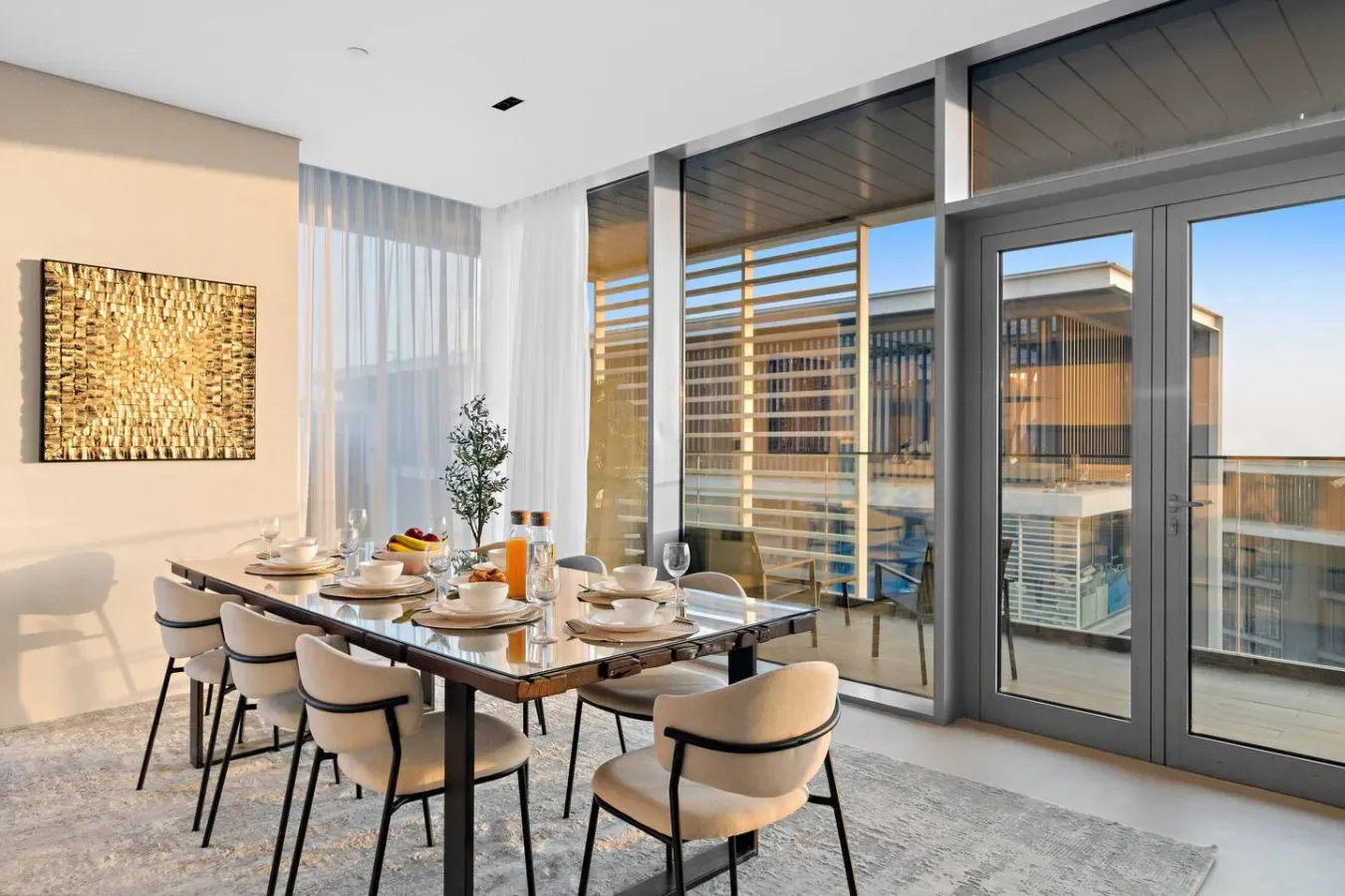 Un comedor luminoso con la mesa puesta junto a grandes ventanales.