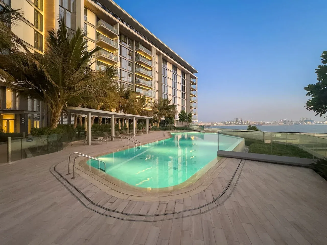 Una piscina al aire libre junto a un edificio moderno, con vistas al agua.