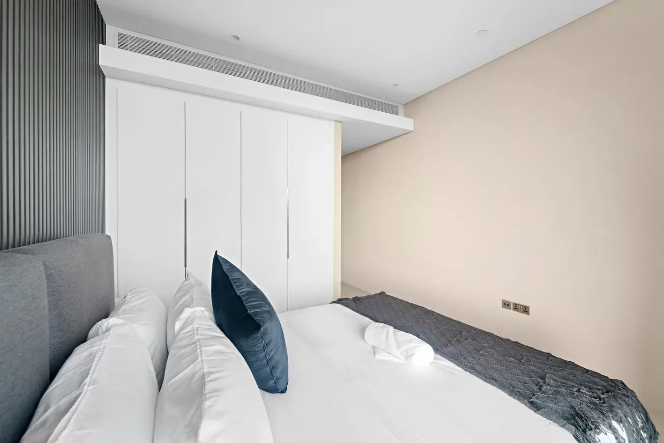 Un dormitorio con ropa de cama blanca y un cojín decorativo azul oscuro.