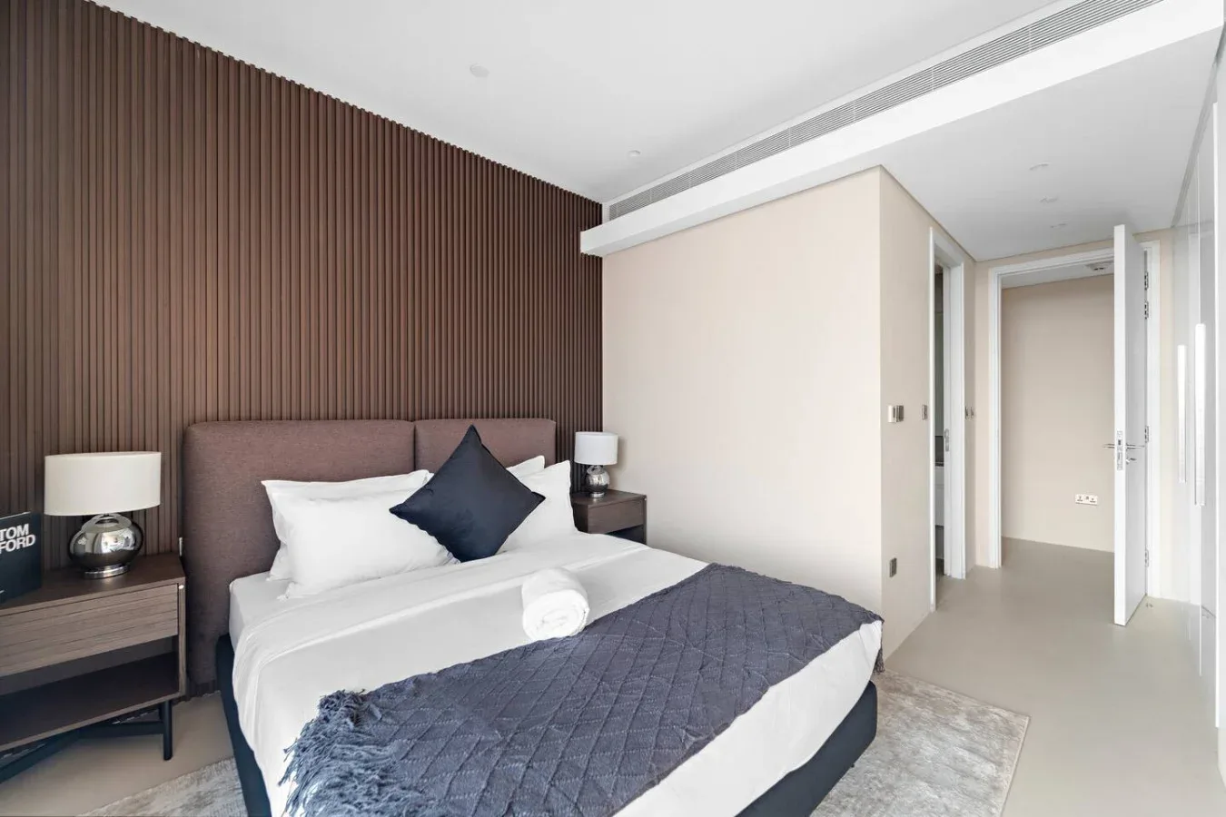 Un dormitorio con una cama bien tendida y una pared oscura texturizada detrás.