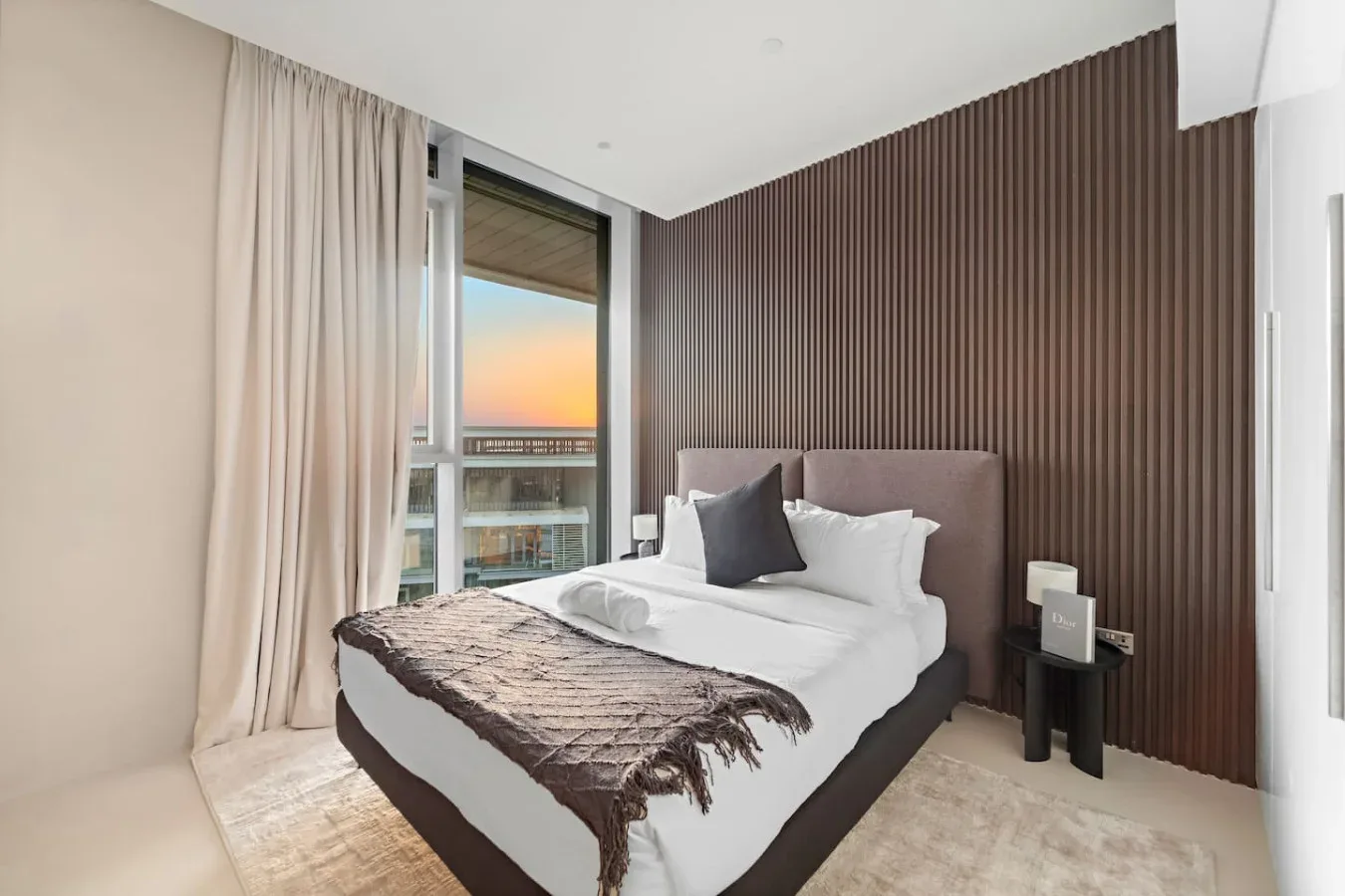 Un dormitorio con una cama bien arreglada junto a una ventana grande.