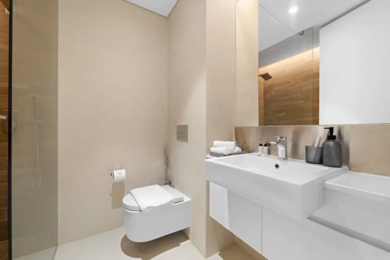 Baño moderno con un inodoro suspendido y un lavabo blanco amplio.