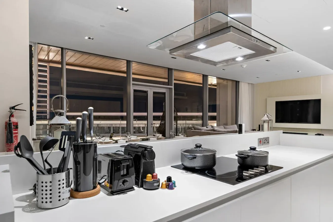 Una cocina moderna con una gran isla blanca y una placa de cocción oscura.