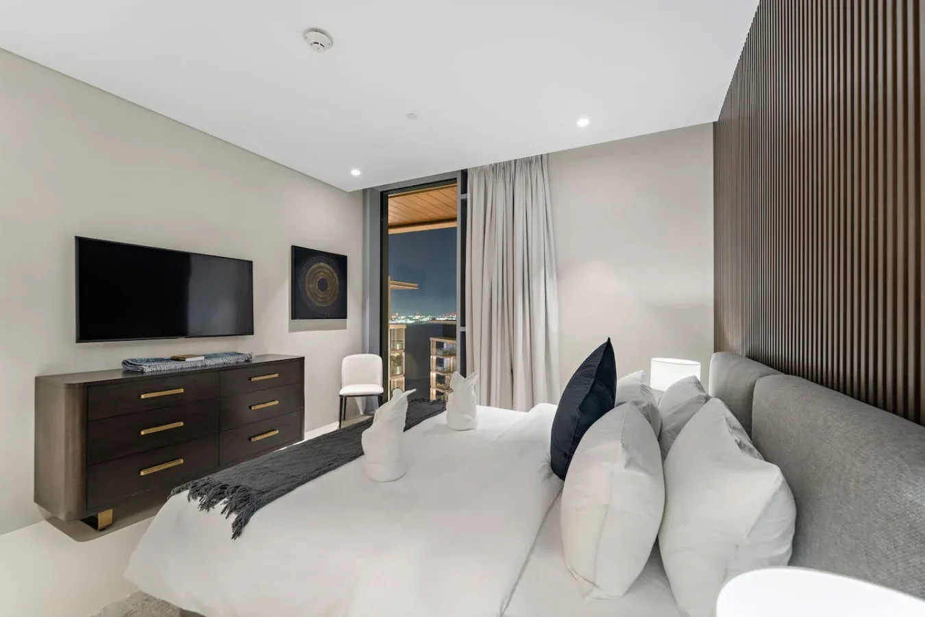 Un dormitorio con una cama, un televisor y cortinas junto a una ventana.