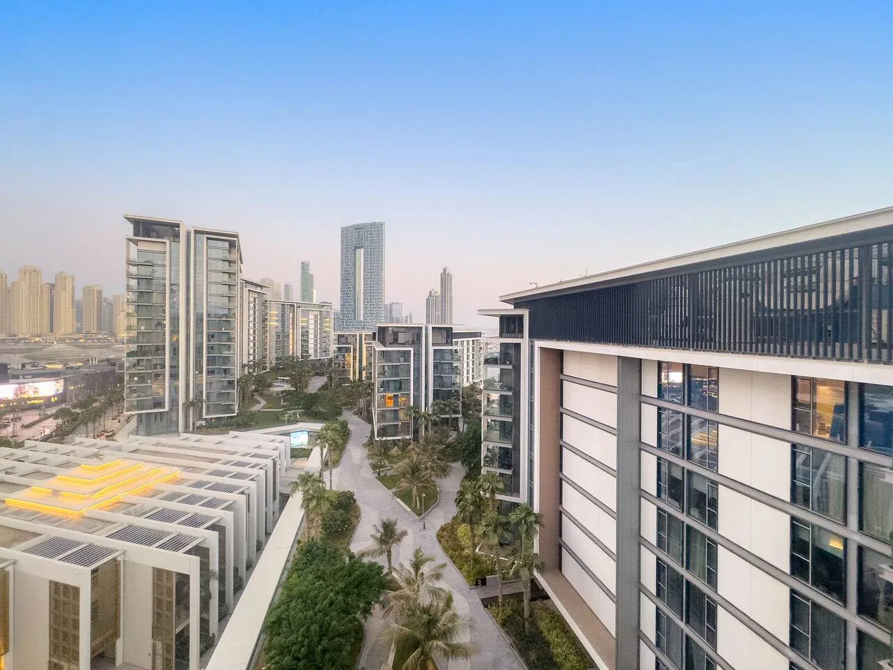Un paisaje urbano de edificios modernos y caminos ajardinados bajo un cielo despejado.