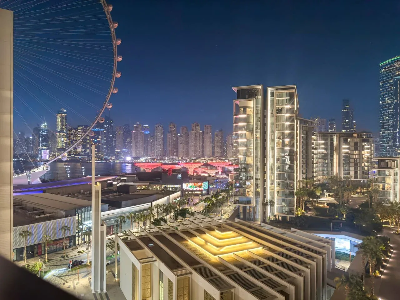 Un horizonte urbano nocturno con edificios altos iluminados y una gran noria.