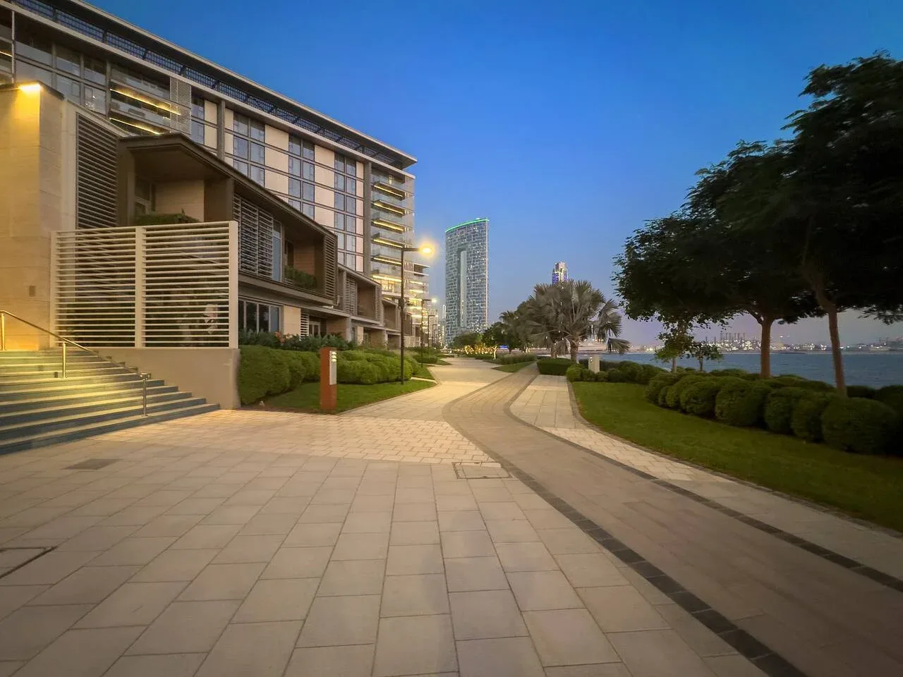 Un camino pavimentado al aire libre se curva junto a jardines y edificios modernos.