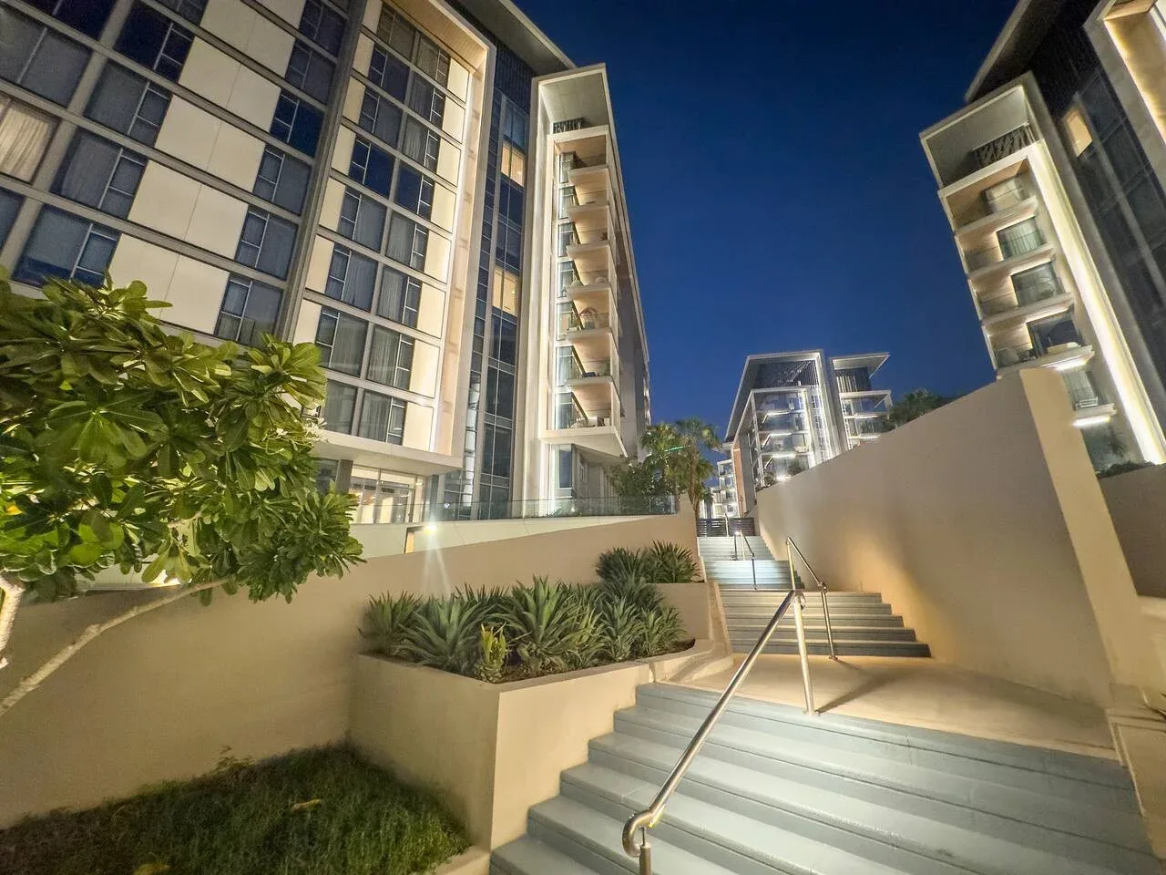Exterior de un edificio moderno de noche, con plantas junto a las escaleras.