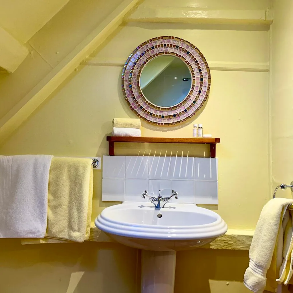 Washbasin and towels in the yellow Thrift en-suite bathroom