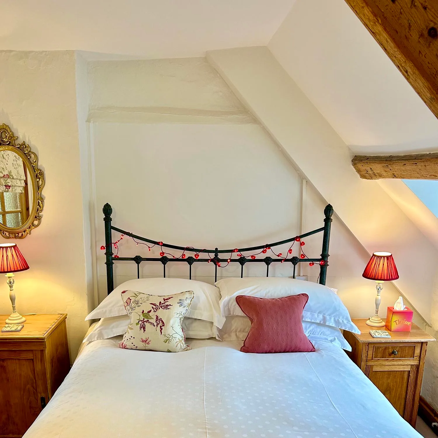 Cast-iron double bed beneath the sloping ceiling in the Thrift room