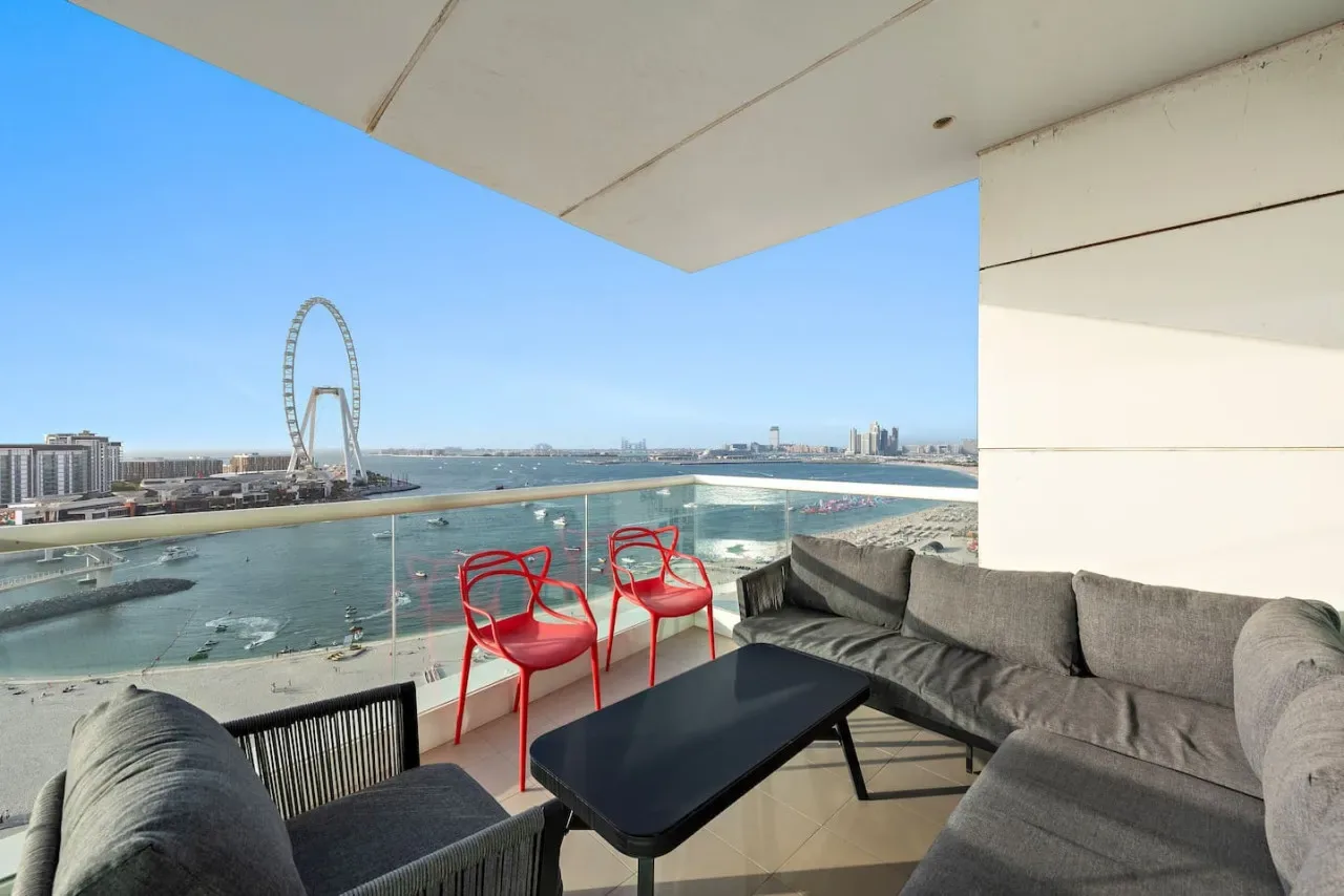 Una zona de estar en el balcón ofrece vistas al paseo marítimo y a un arco distintivo.