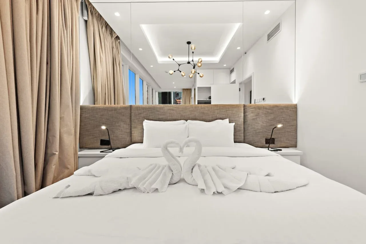 Un dormitorio luminoso con una cama bien tendida y toallas dobladas.