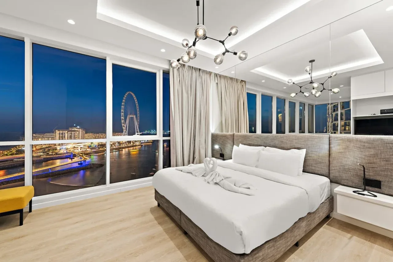 Un dormitorio luminoso con una cama grande y ventanales con vistas a la ciudad.