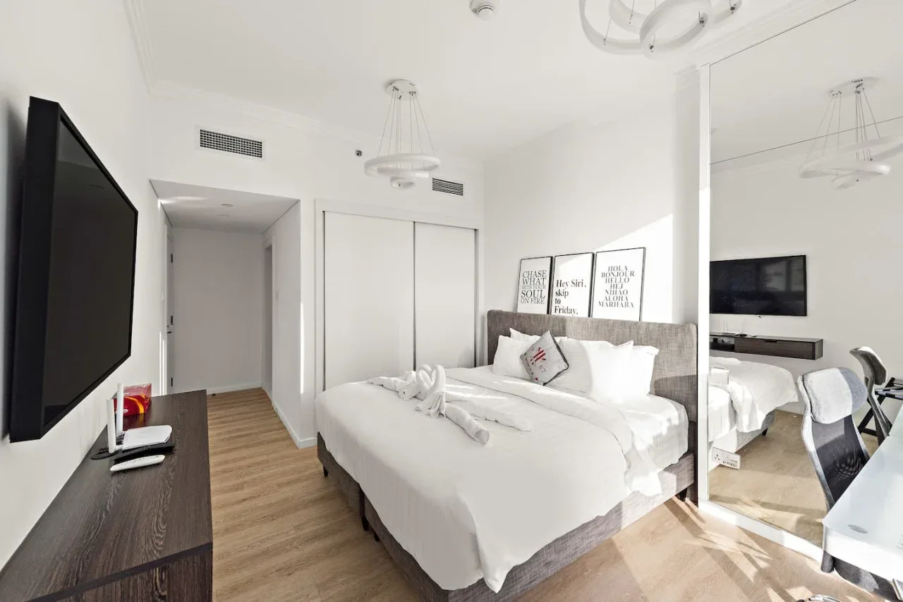 Un dormitorio luminoso con una cama bien tendida y puertas de armario espejadas.