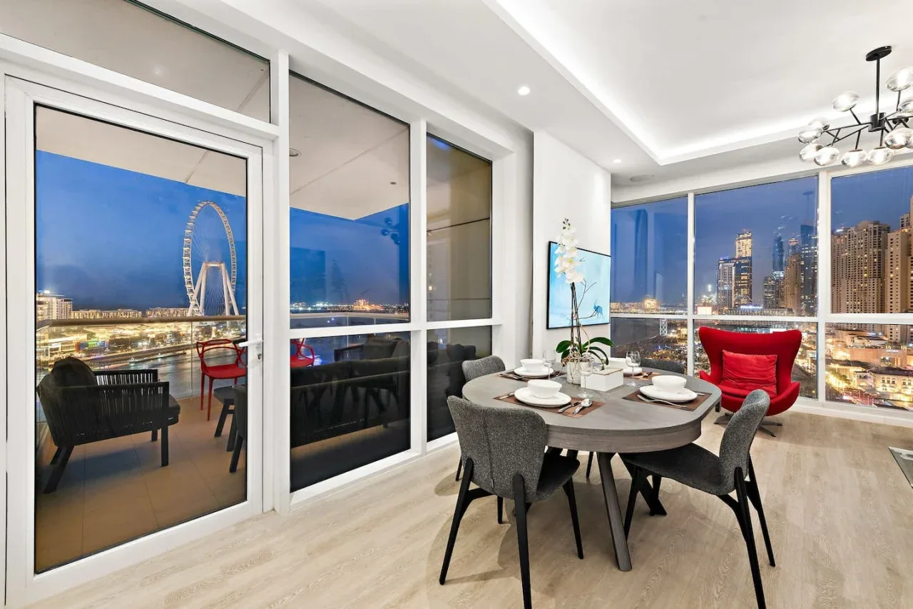 Comedor con mesa y asientos junto a ventanales con vistas a la ciudad.