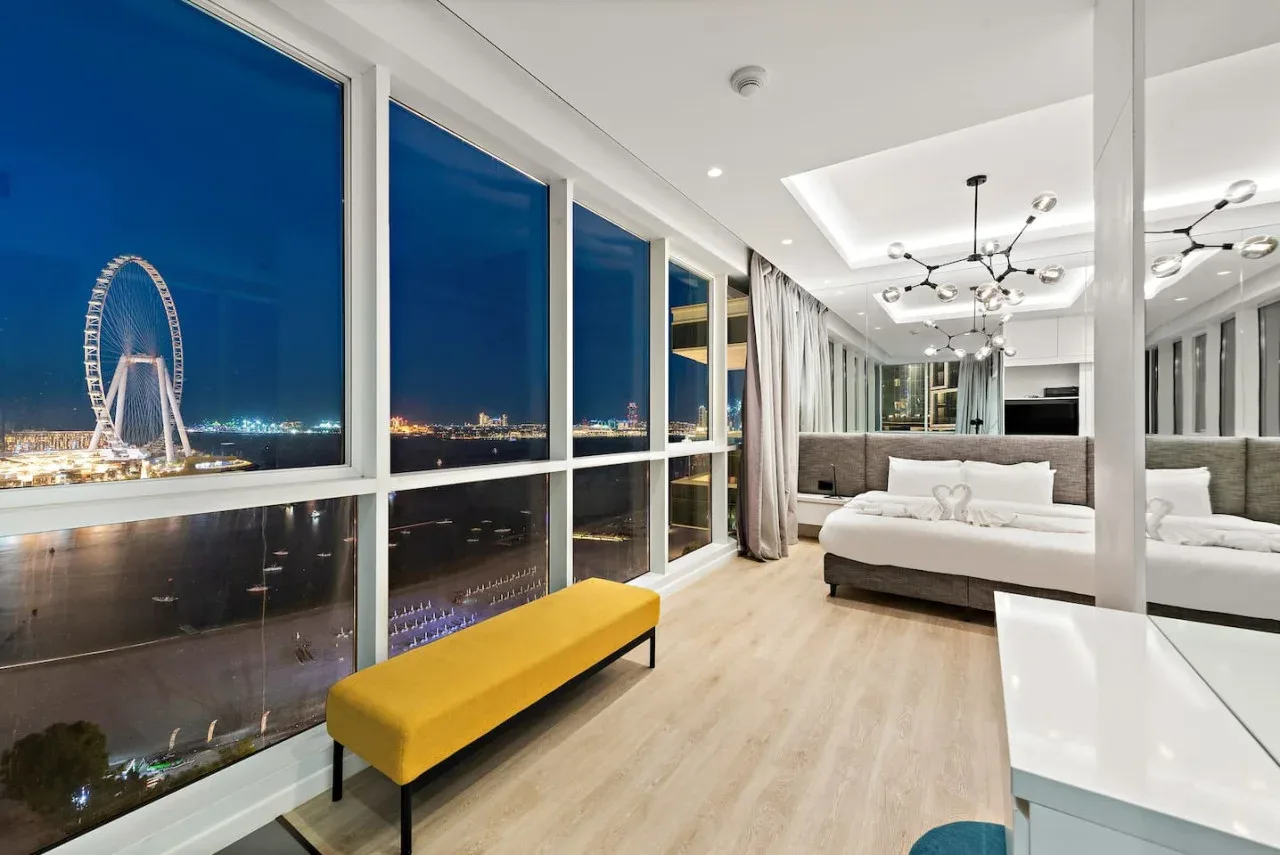 Un dormitorio luminoso con ventanales que ofrecen vistas de la ciudad por la noche.