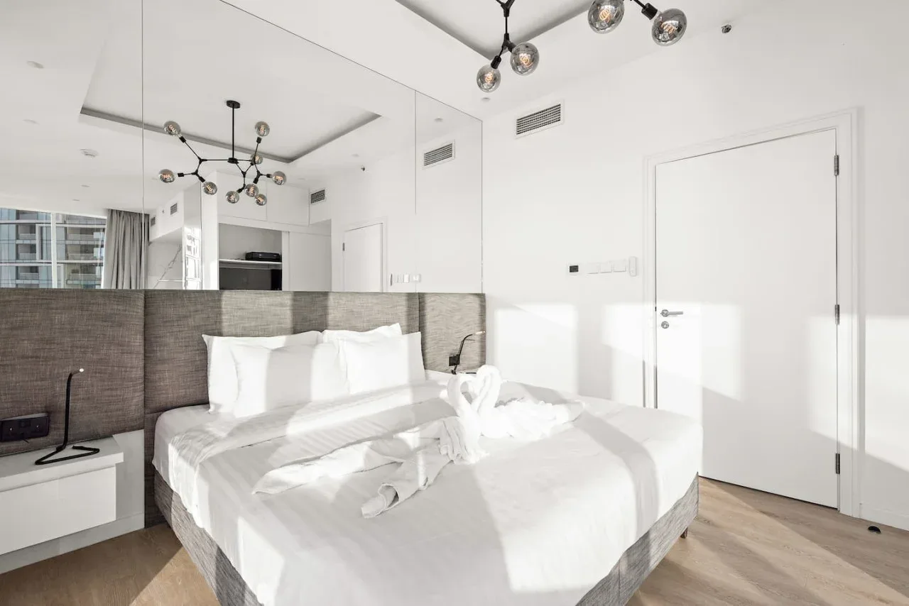 Un dormitorio luminoso con una cama grande y una pared de espejo.