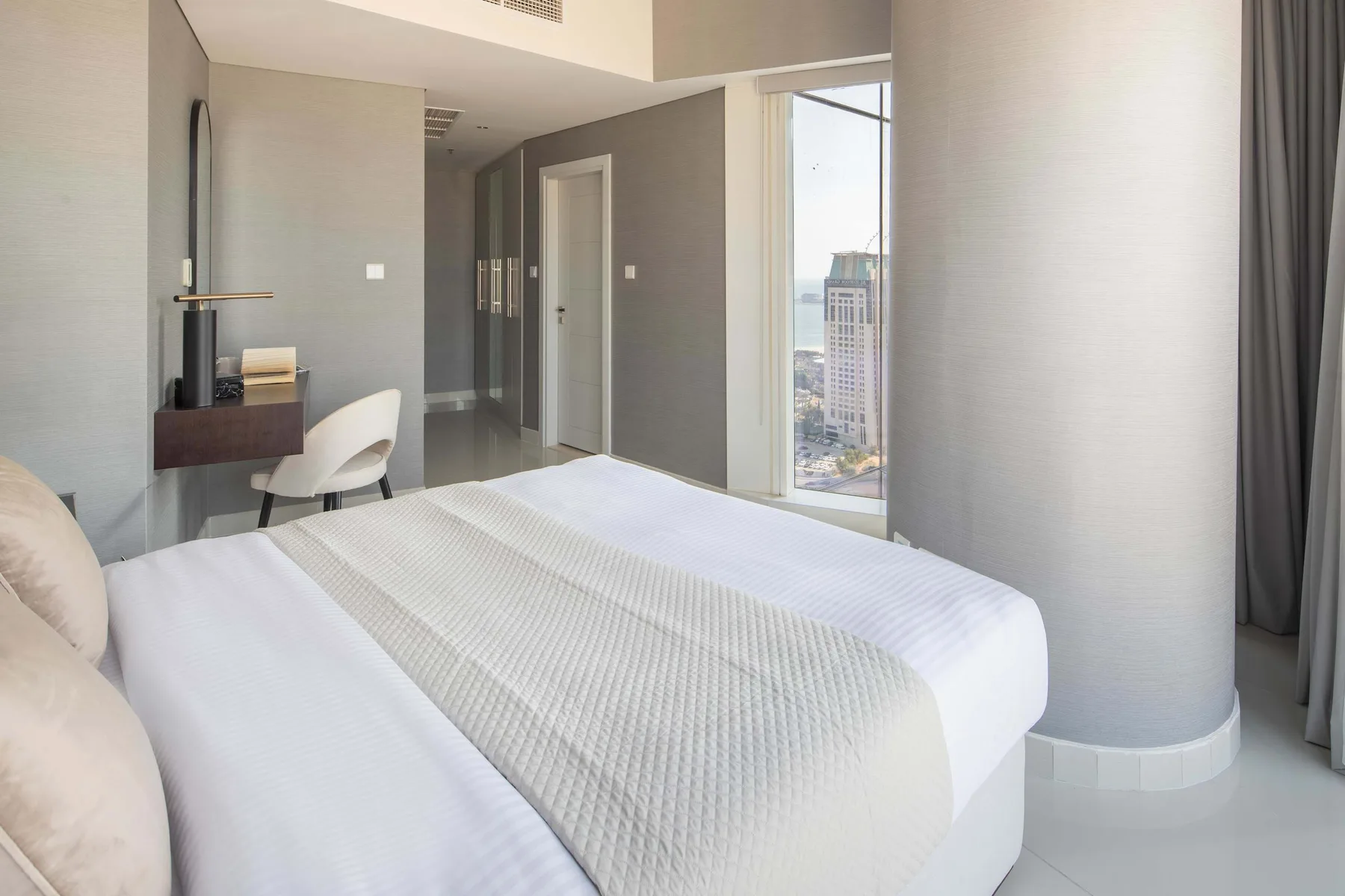Un dormitorio moderno con una cama grande, un escritorio y una ventana de suelo a techo.