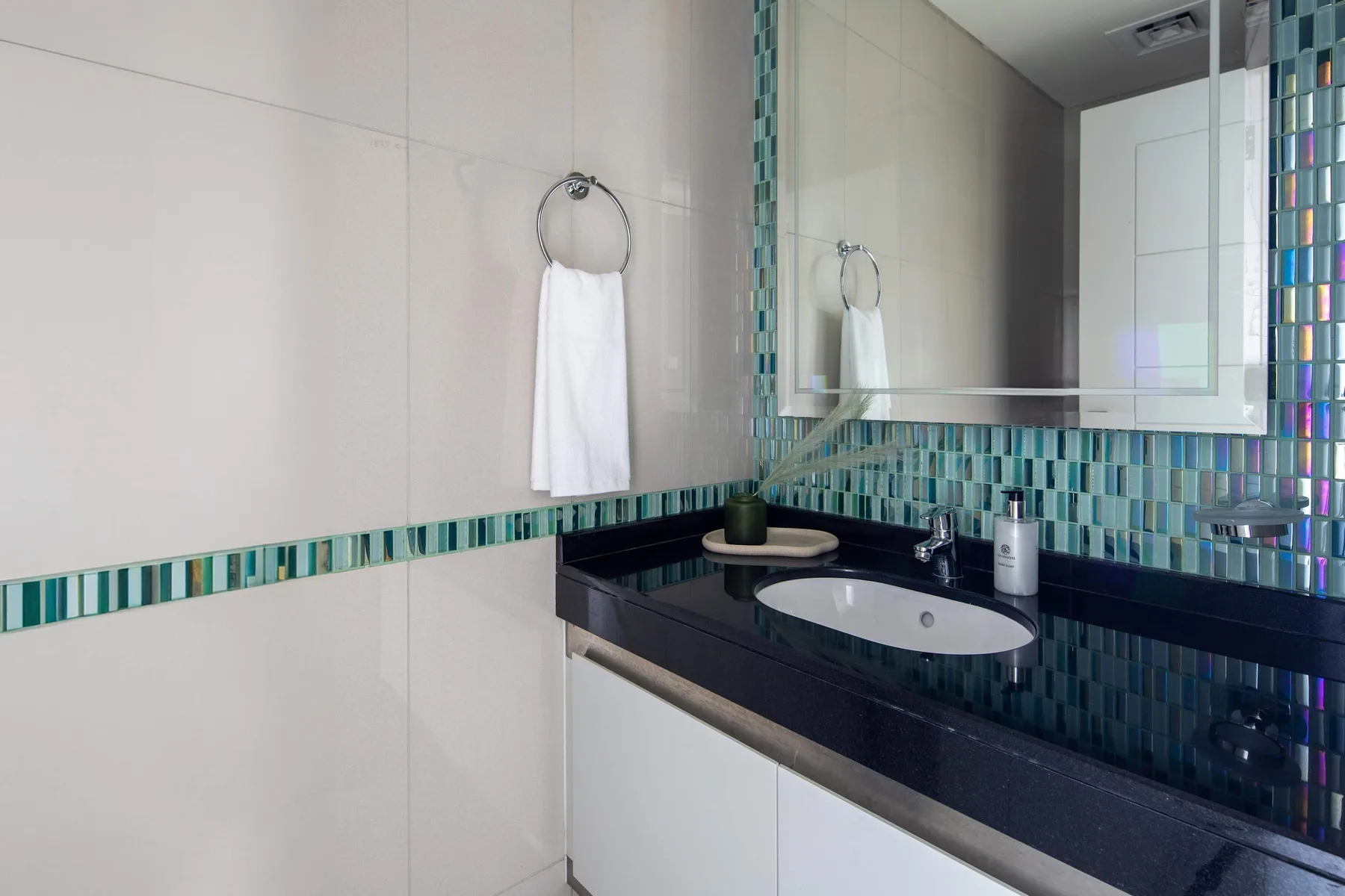 Un lavabo de baño con encimera oscura, fregadero y espejo de pared.
