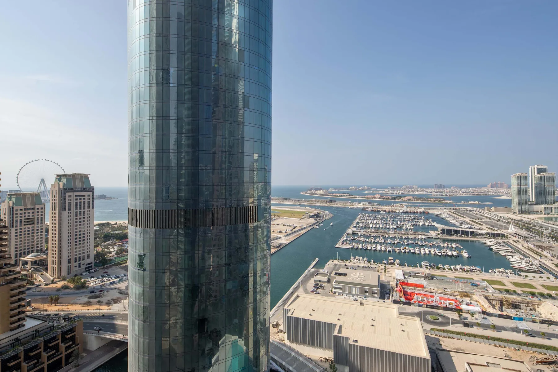 Puerto y marina urbanos vistos desde arriba, con una torre de vidrio en primer plano.