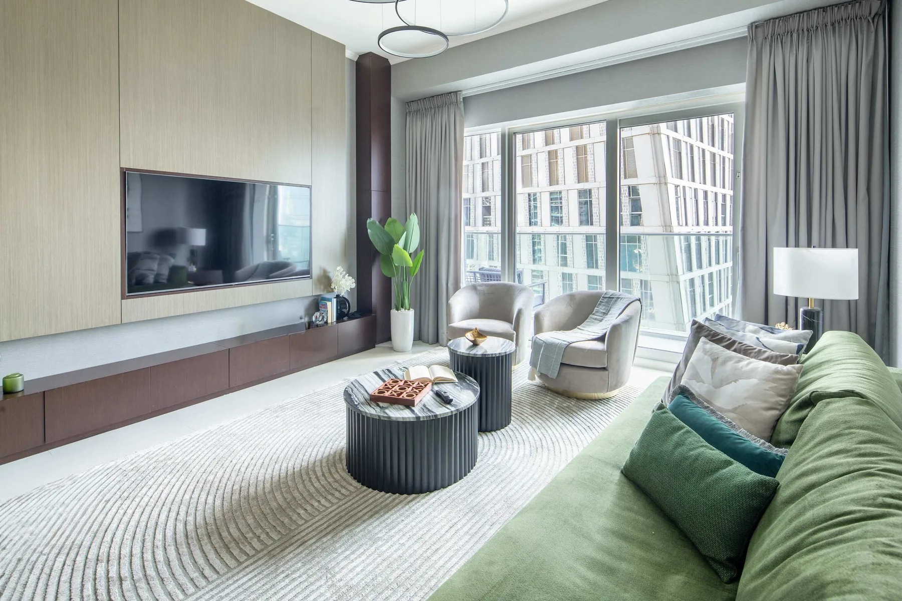 Una luminosa sala de estar con asientos, un televisor y grandes ventanas.