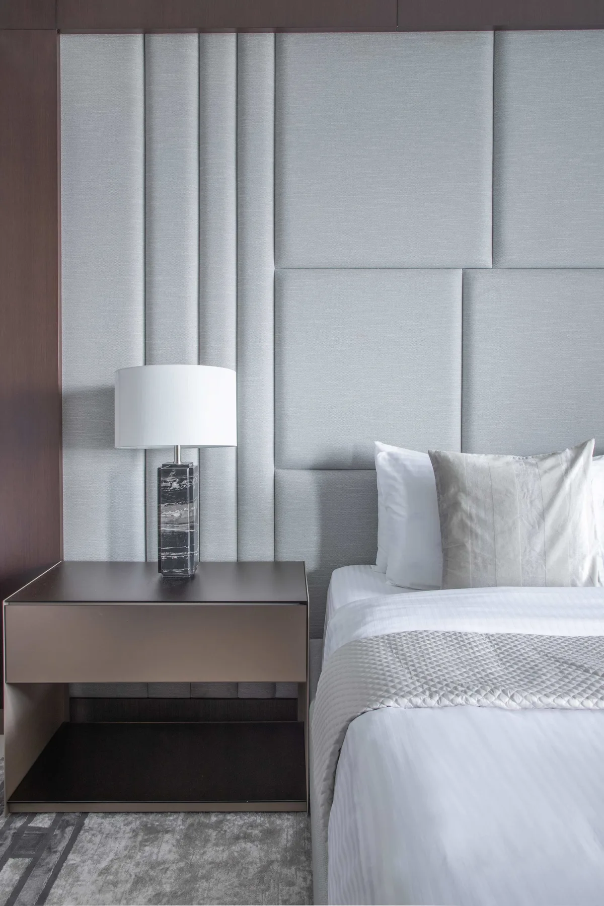 Un dormitorio con una cama junto a una mesita de noche y una lámpara.