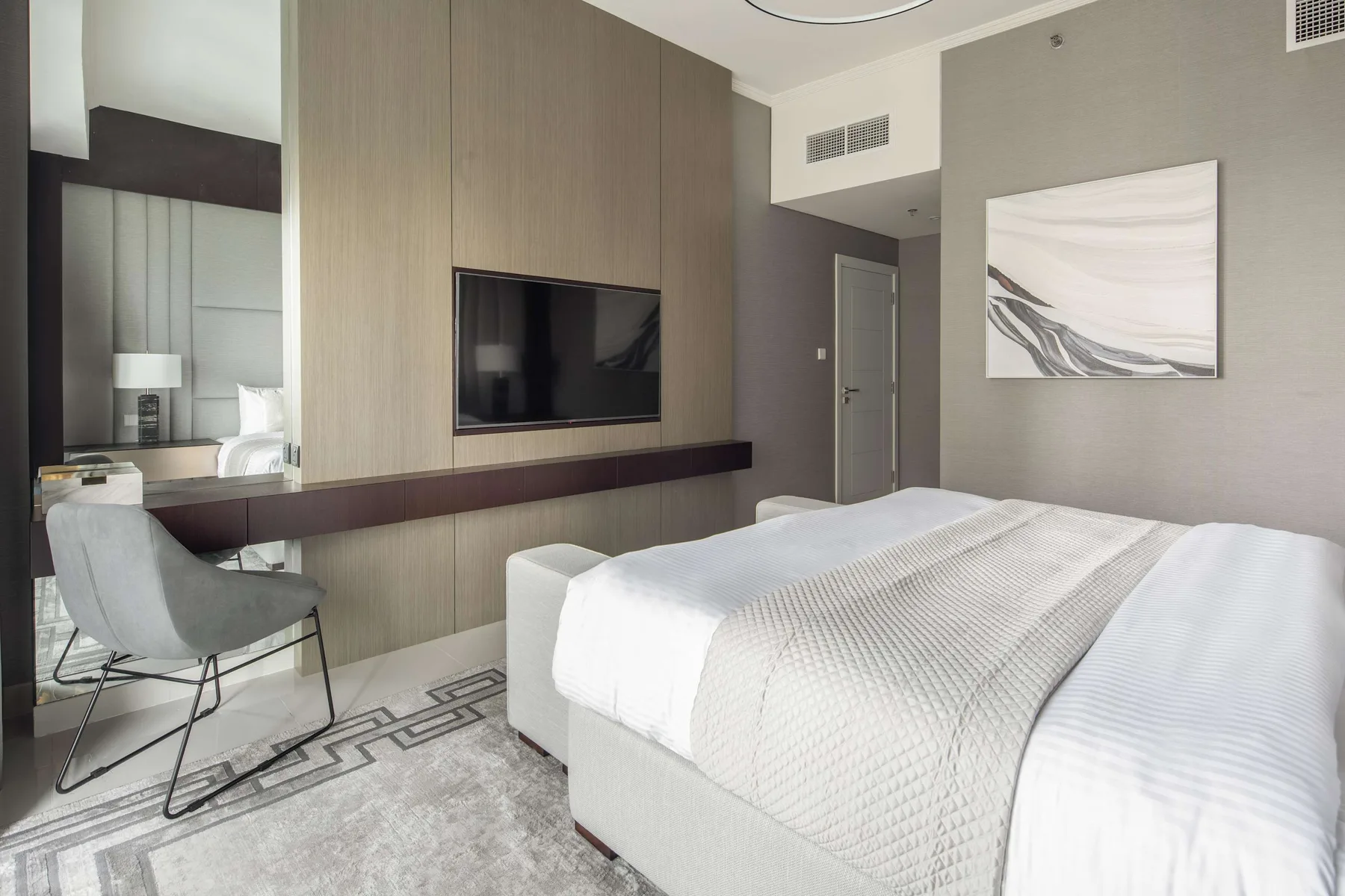 Un dormitorio con una cama grande, un televisor montado en la pared y un escritorio.