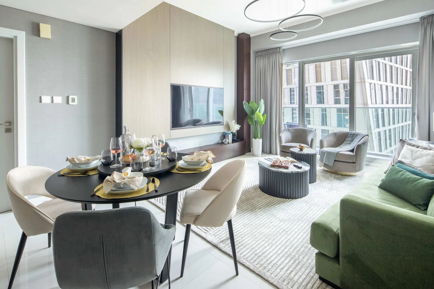 Una sala moderna con mesa de comedor, asientos y grandes ventanales.