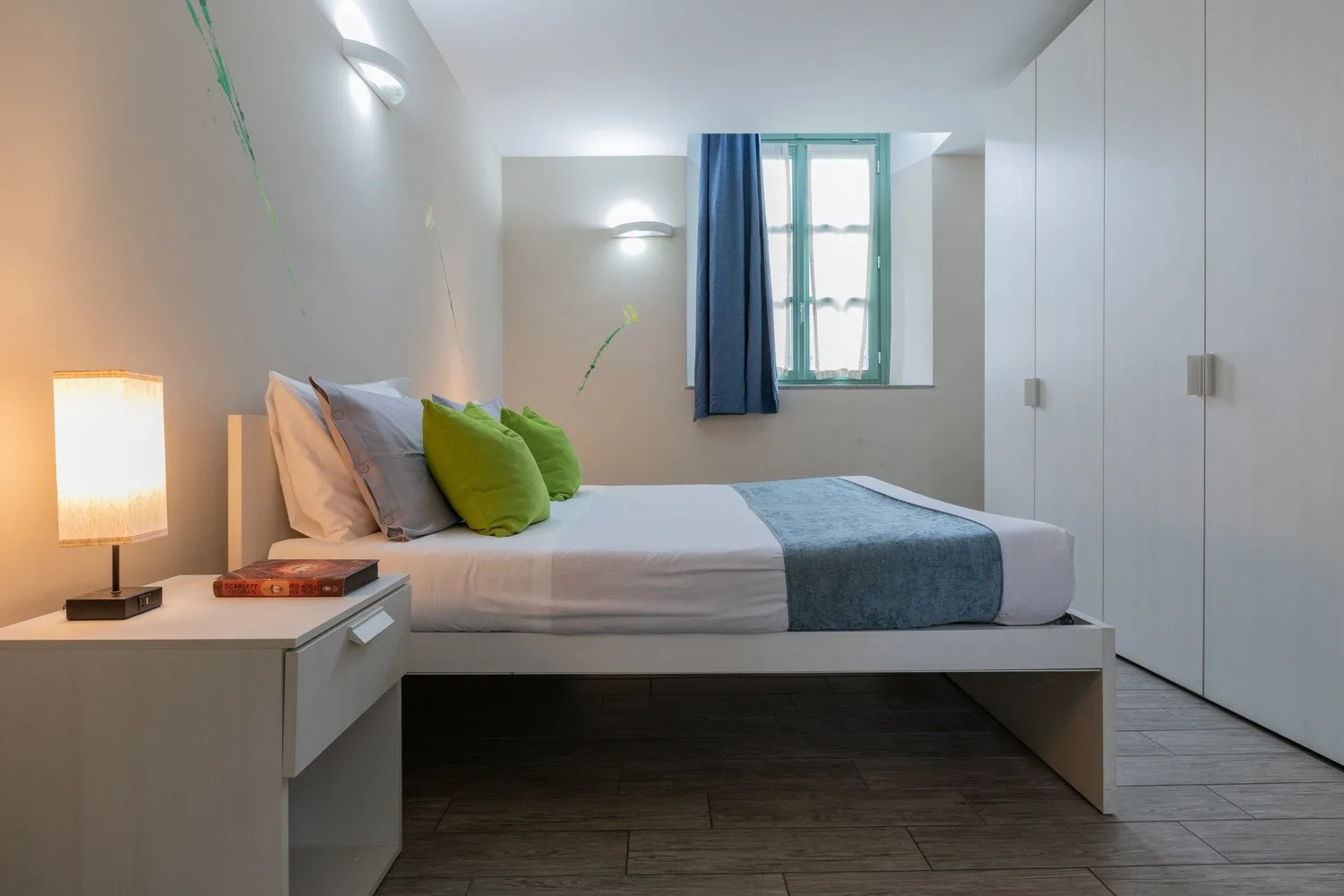 Un dormitorio con una cama bien arreglada y una ventana pequeña.