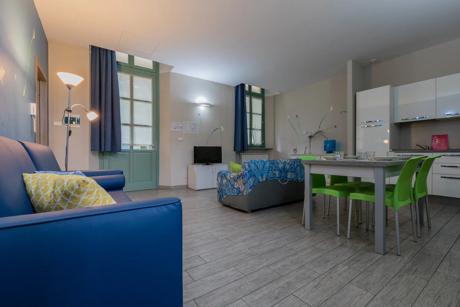 Una sala de estar y comedor con asientos azules y un conjunto de comedor verde.